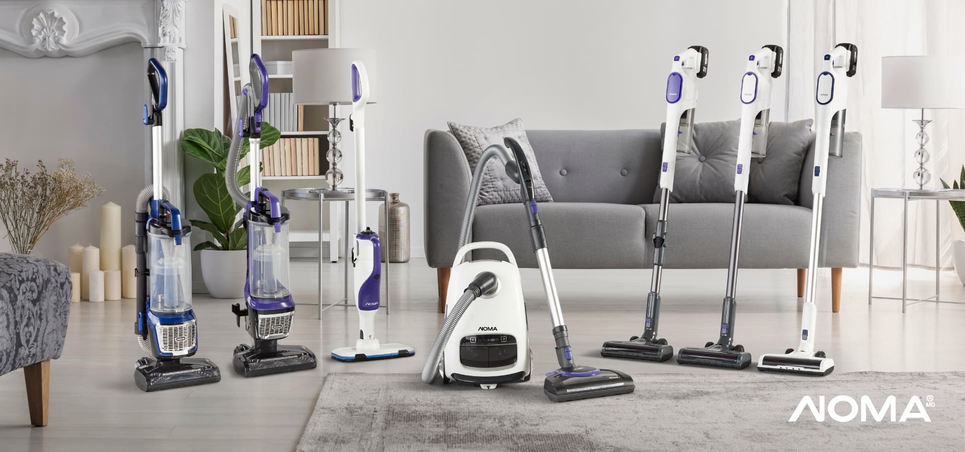 An assortment of eight styles and sizes of NOMA vacuums in a living room. 