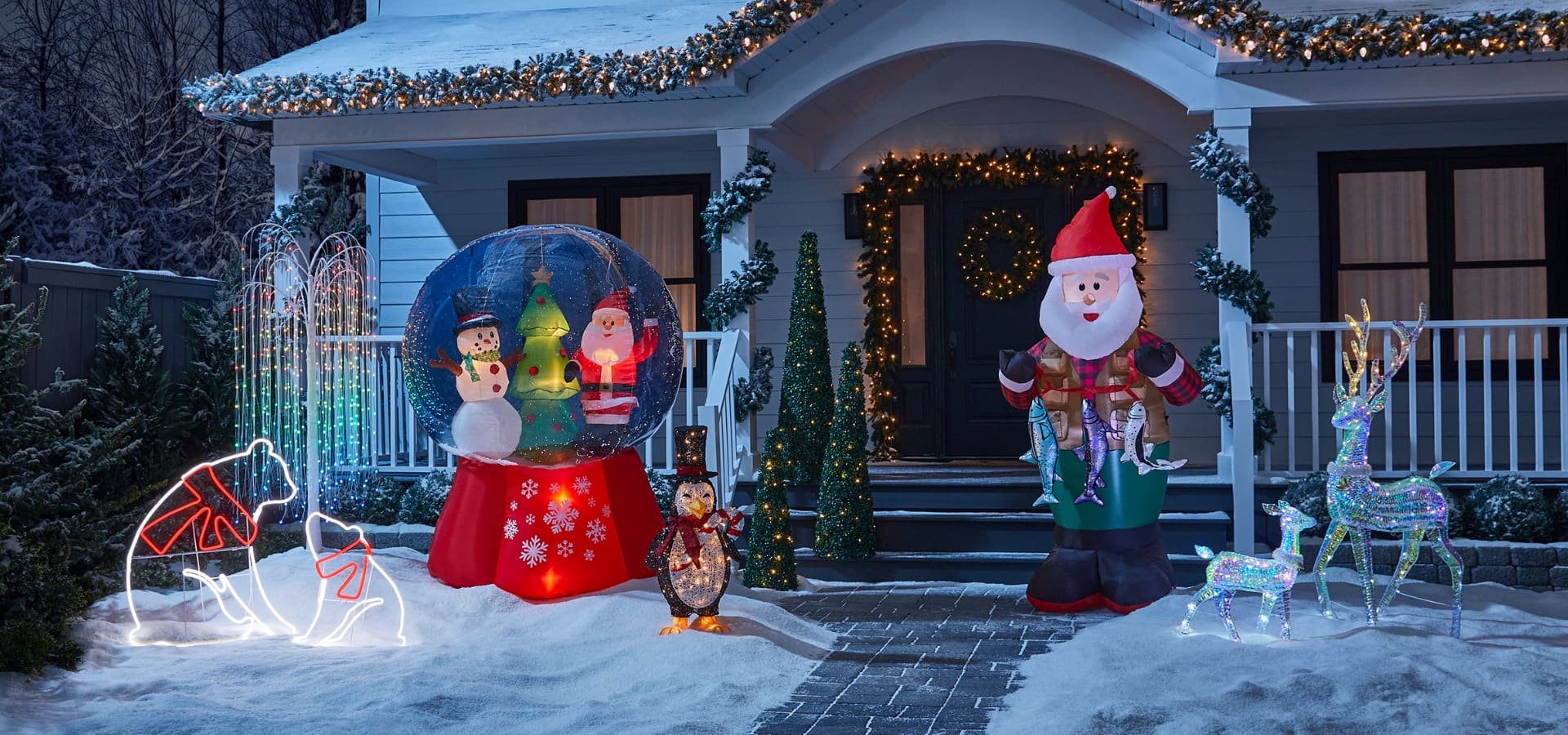 An assortment of pre-lit wireform figures on a snowy lawn including a reindeer, bear and ornament