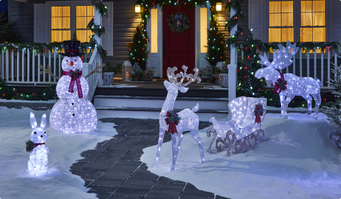 A range of CANVAS Arctic White pre-lit wireform figures on a snowy lawn