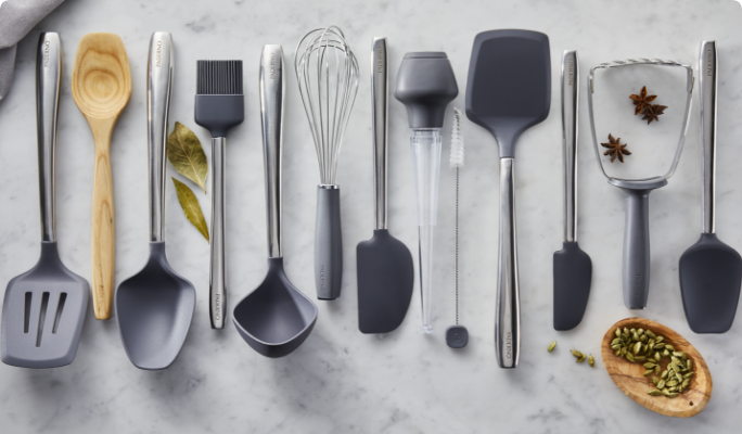 An assortment of PADERNO serving and cooking utensils on a marble countertop. 