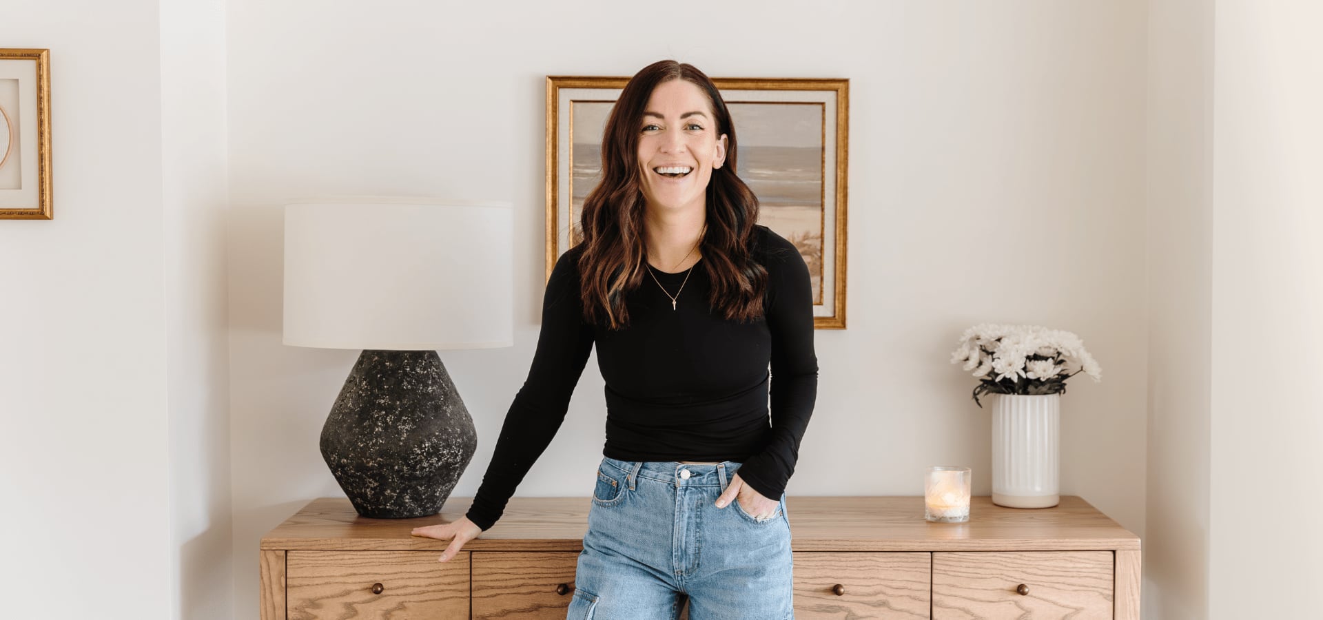 Influencer Sammy Sylvester in a living rooms leaning against a chest of drawers 