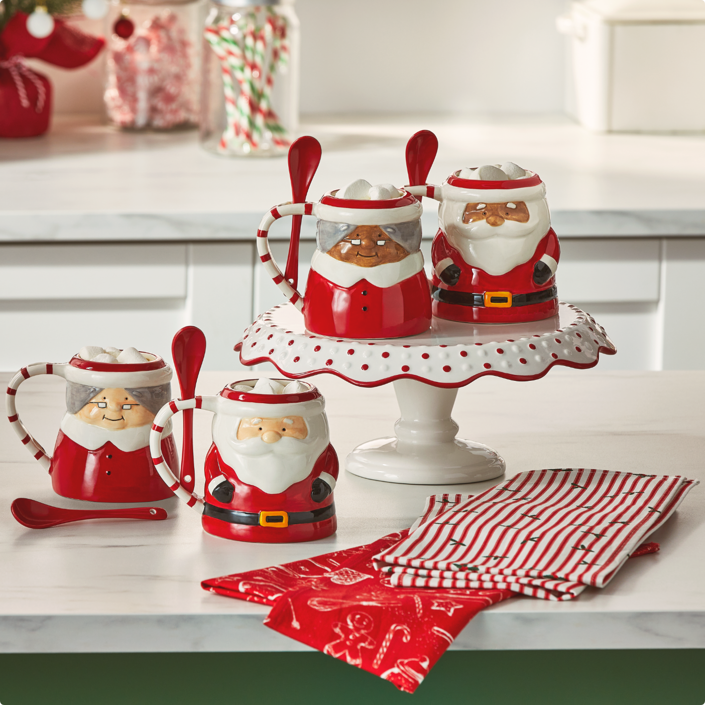 Assortiment de tasses et torchons du Père Noël et de Mère Noël sur un comptoir de cuisine.