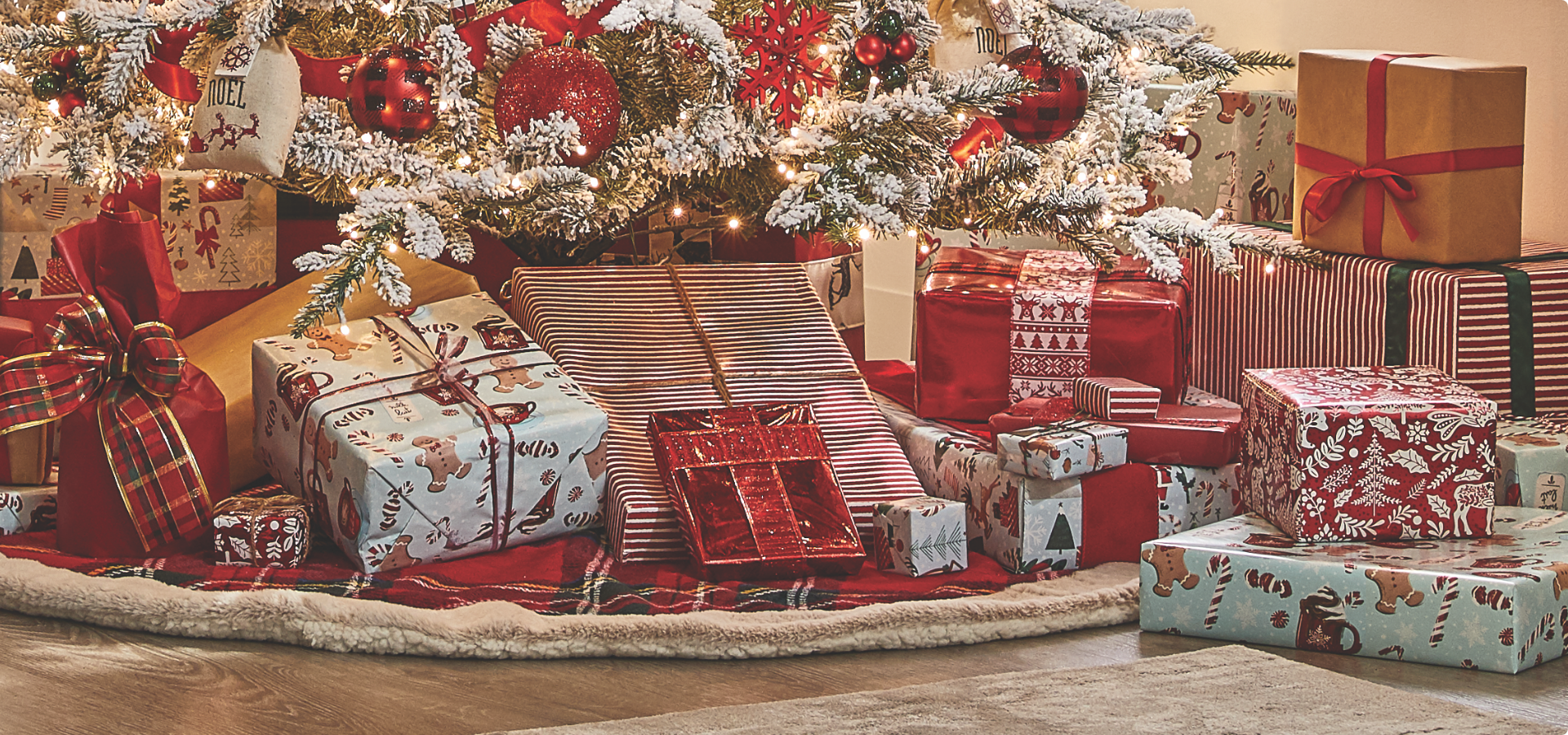 A variety of gifts wrapped under a white flocked Christmas tree.