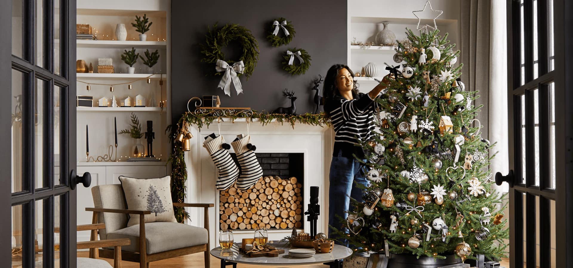 A woman decorating a living room and tree with CANVAS Night Before Christmas decorations. 