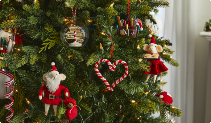 Ornements l’Atelier du père Noël de CANVAS accrochés à un arbre de Noël.