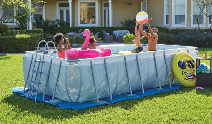 An adult and three children swimming and playing in a rectangular Coleman steel Frame Pool. 