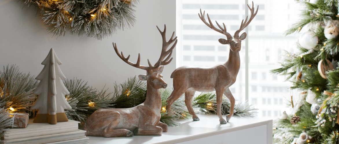 CANVAS Wood-like deer figurines, a ceramic tree and assorted decor on a mantle. 