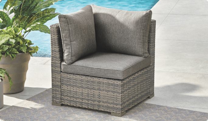 CANVAS Bala Corner Seat set up on a poolside patio with cushions and potted plants.