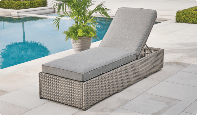 CANVAS Bala Lounger set up on a poolside patio with a potted plant. 