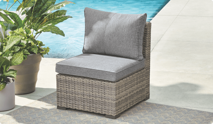 CANVAS Bala Middle Chair set up on a poolside patio with potted plants. 