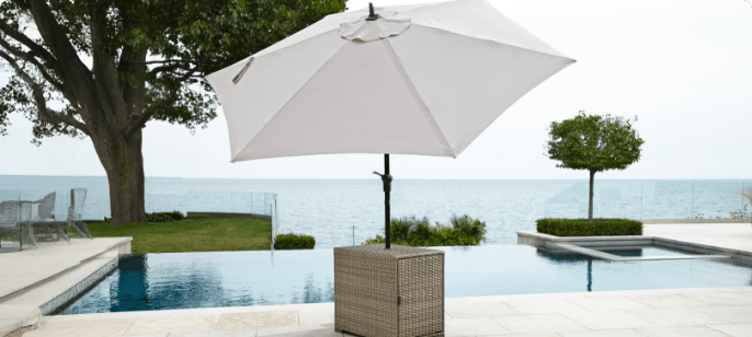 CANVAS Bala Patio Umbrella Table set up on a poolside patio with a grey umbrella.