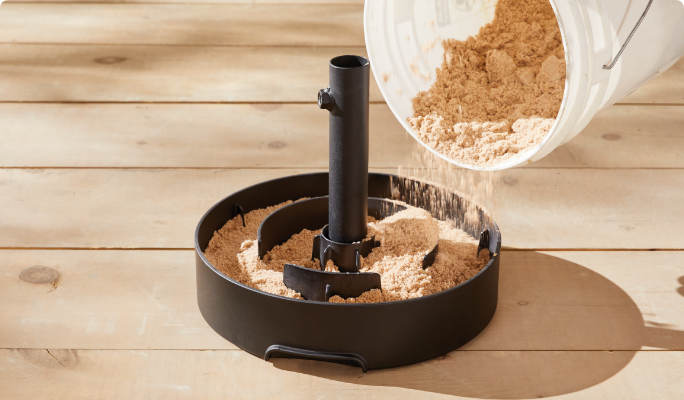 A CANVAS Monte Low Profile Umbrella Base being filled with sand.