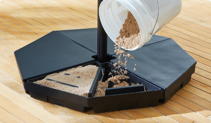 A CANVAS Offset Umbrella Base being filled with sand.