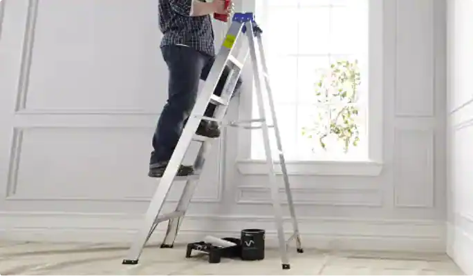 A painter climbs an aluminum step ladder in a white room.