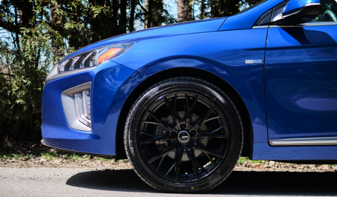 Un pneu toute-saison sur une voiture de sport bleue.