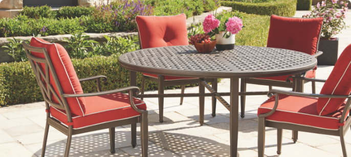 A CANVAS Coventry Round Dining Table and three cushioned chairs in a garden patio.
