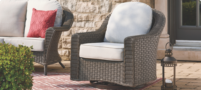 Un fauteuil pivotant coulissant CANVAS Summerhill avec des coussins blancs sur une terrasse. 