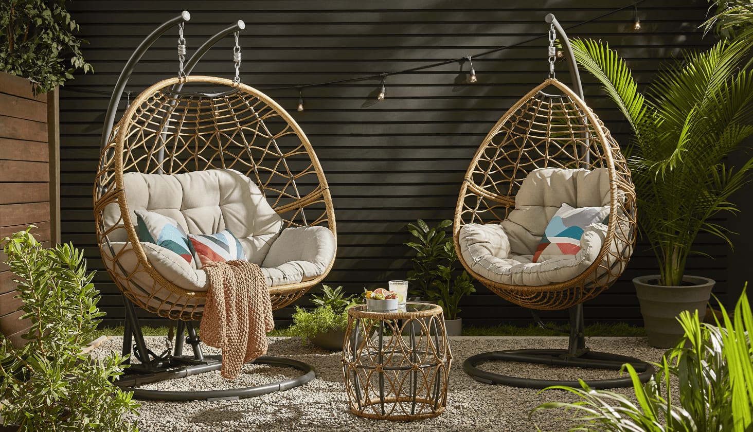 Two CANVAS Sydney Egg swing chairs with side table on a backyard patio.