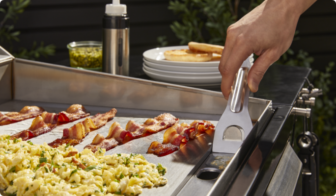 A close up shot of a person scraping grease into the grease tray.