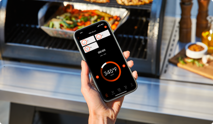 A person holding a smart phone in front of the Grill with the lid open.