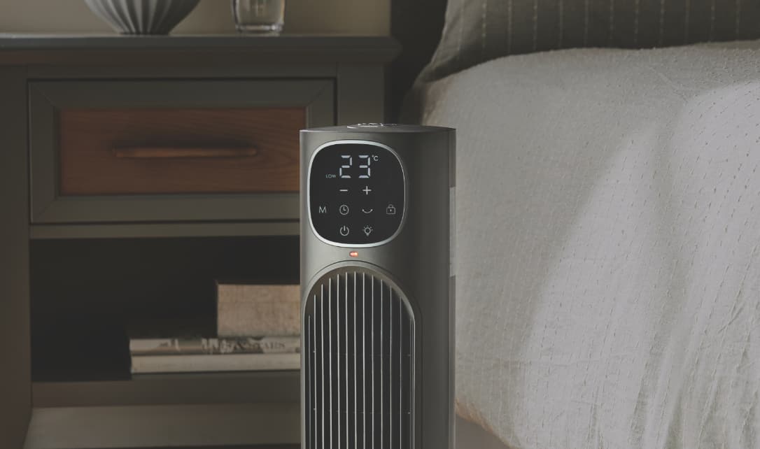 A Noma Tower Heater next to a bed in a bedroom.