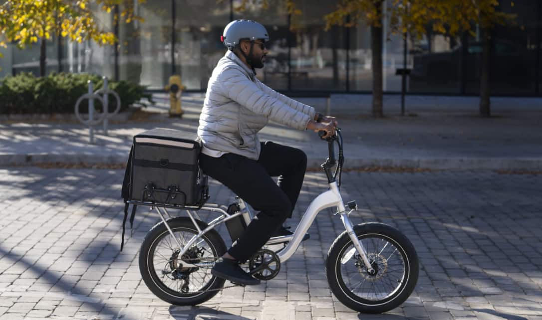 A man riding an e-bike with throttle on a city street. 