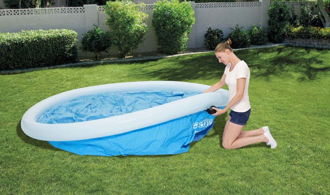 A woman inflating the top ring of a fast set pool. 