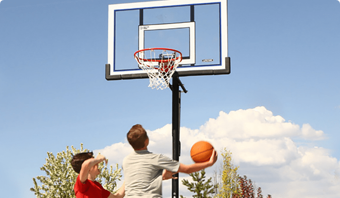 Two kids playing basketball in a driveway with a Lifetime 52-in Adjustable Portable Net System.