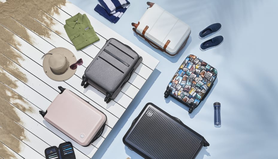 A variety of luggage pieces, clothing and travel accessories rest on a sand-covered deck.