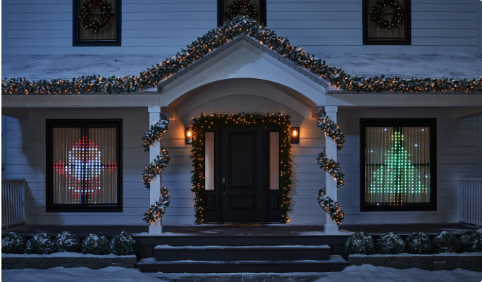 A house with lights, garlands and a NOMA Creative Lightshow curtain display in a window. 