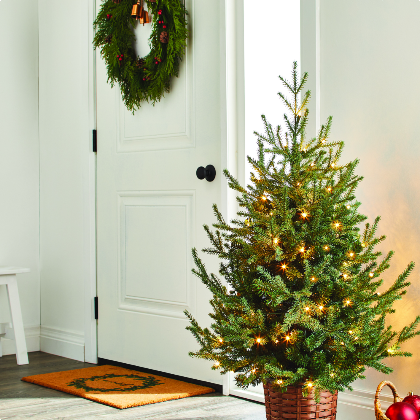 An indoor entryway with a CANVAS Potted Tree, cedar heart wreath and a Coir mat.