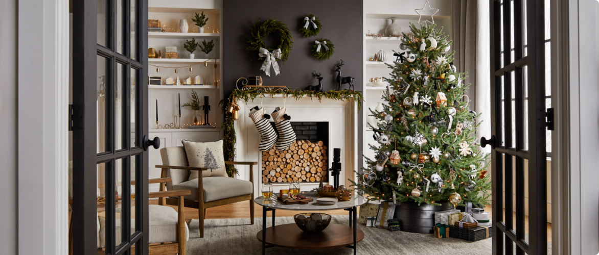 A living room with a fireplace decorated with garland, stockings, wreaths, a Christmas tree and various other tabletop holiday decorations.