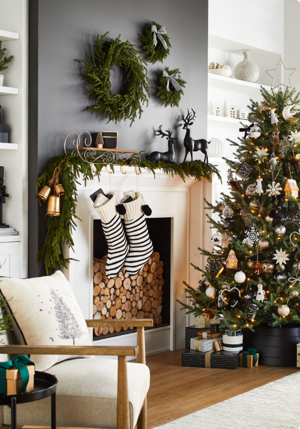 A living room with a fireplace decorated with garland, stockings, wreaths, a Christmas tree and various other holiday decorations.