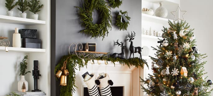 A living room with a fireplace decorated with garland, stockings, wreaths, a Christmas tree and various other holiday decorations.