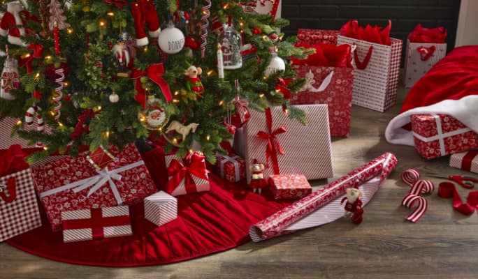 A roll of gift wrap and wrapped gifts under a Christmas tree. 