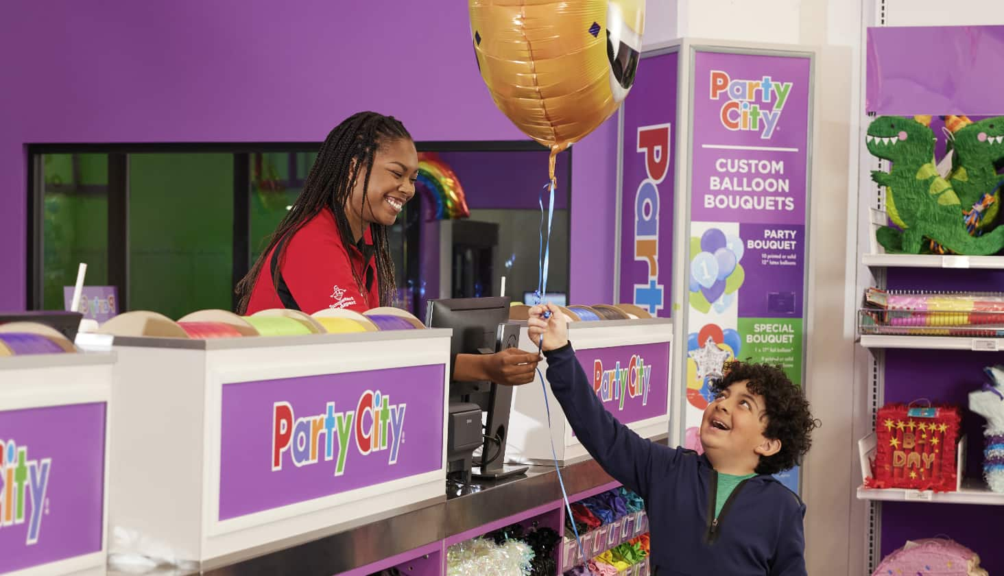 Un employé remet un ballon à un enfant au comptoir de retrait des bouquets de ballons personnalisés.