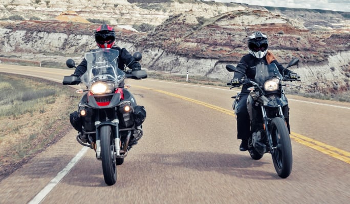 Deux motocyclistes circulant sur une route panoramique.