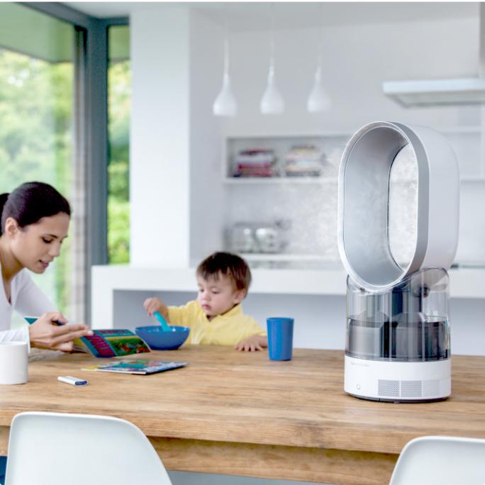 A humidifier sits on a kitchen table next to a woman and child.