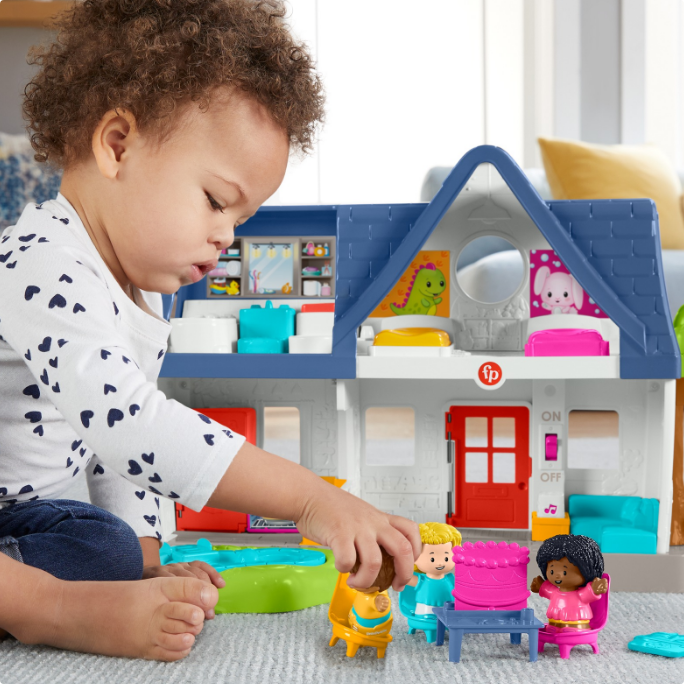 A toddler plays with a Fisher-Price playset.