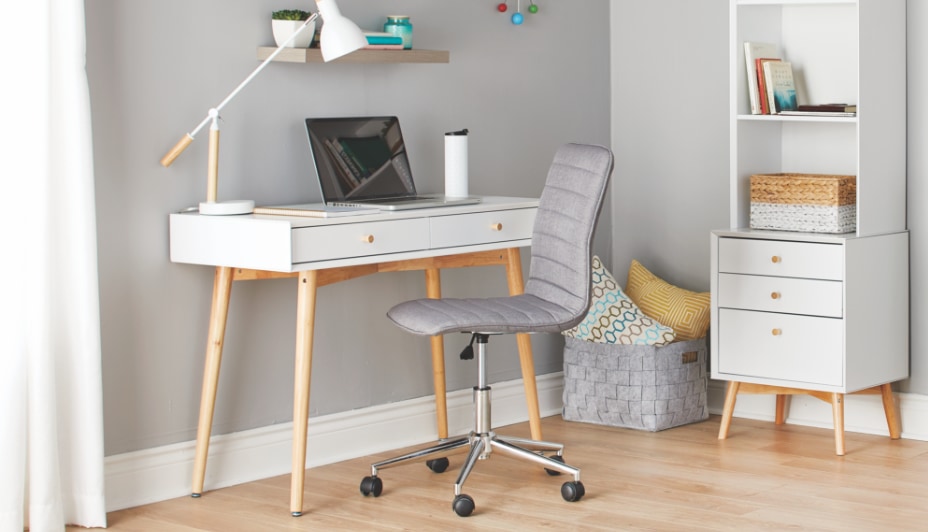 A modern home office setup with a desk, swivel chair and shelving unit.