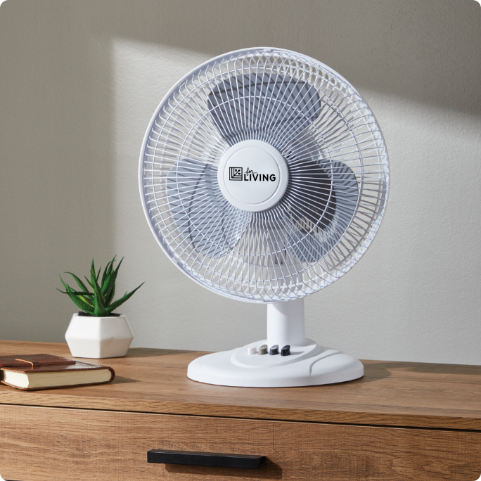 A white For Living table fan on a wooden surface.