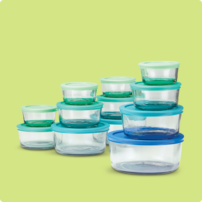 A set of glass Anchor Hocking food storage containers with blue lids.