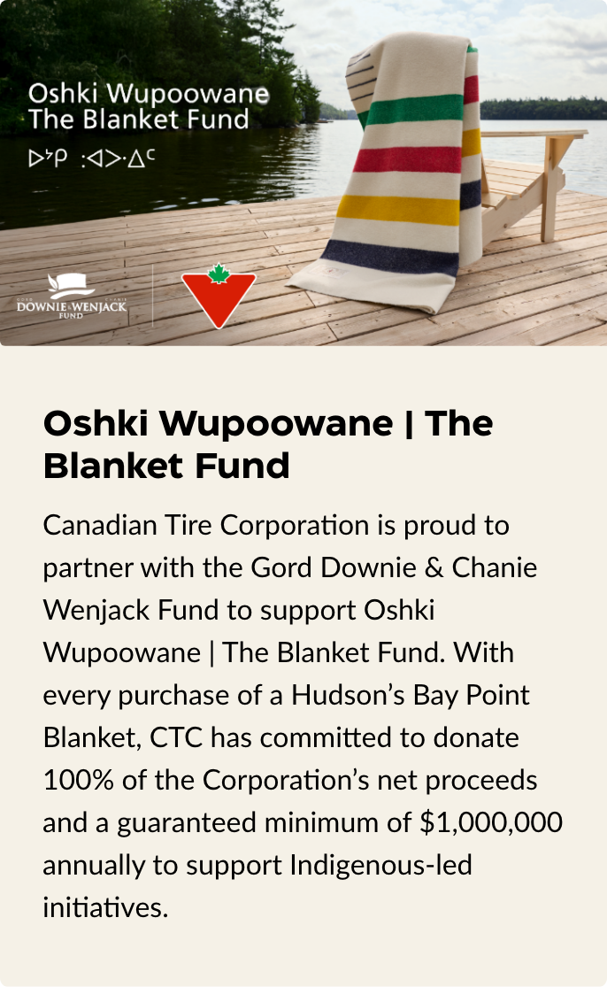 Hudson's Bay Point Blanket is draped on a Muskoka chair highlighting the Oshki Wupoowane Blanket Fund charity. 