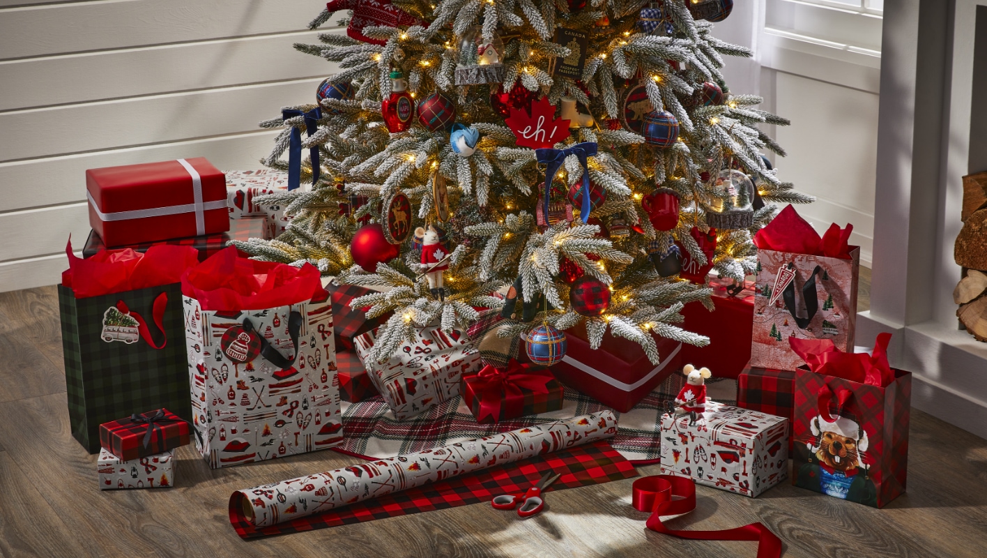 A Christmas tree with red and gold decorations is surrounded by wrapped presents and a roll of wrapping paper on the floor.