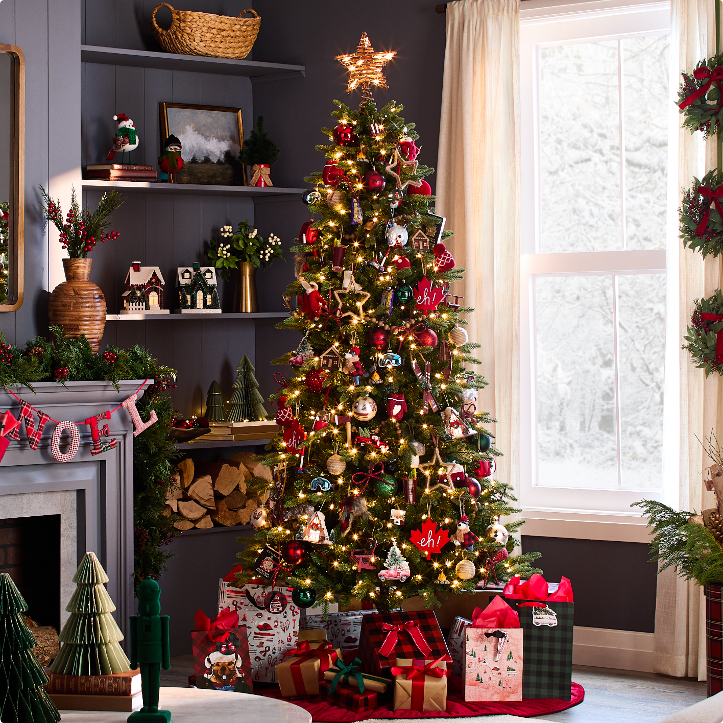 A decorated Christmas tree with presents underneath stands in a cozy living room next to a fireplace and window with snowy view.