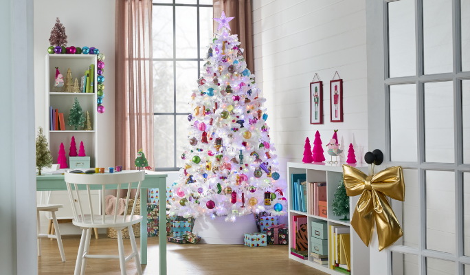 Une pièce festive avec un arbre de Noël blanc orné de décorations colorées et une boucle dorée sur la porte.