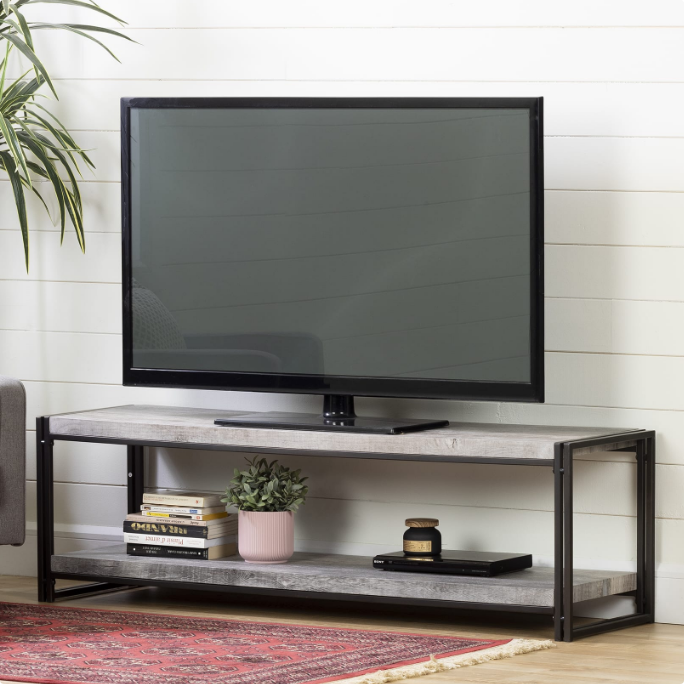 A TV on a modern media console with a lower shelf for storage.