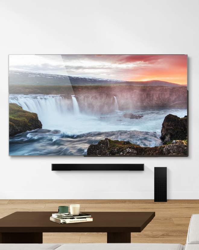 A mounted TV on a wall above a soundbar in a living room.