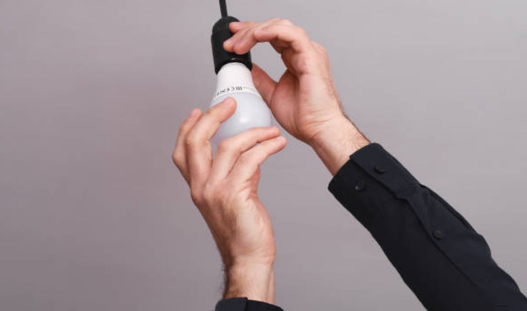 Une personne installant une ampoule et illustrant le type de culot.