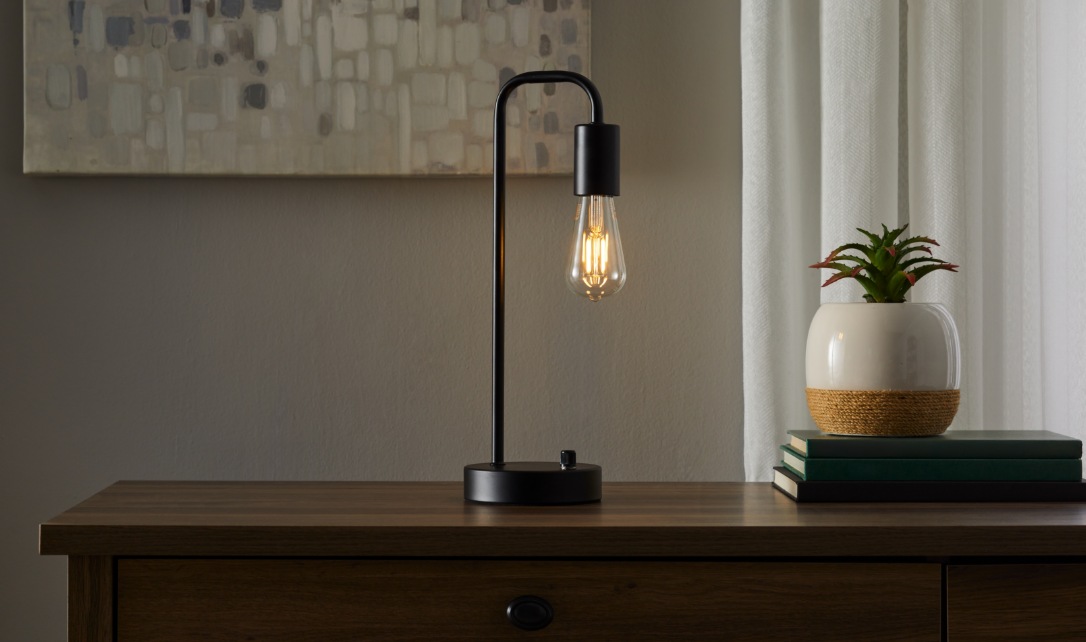 Une personne installant une ampoule à DEL dans un luminaire de plafond.